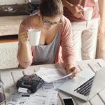 top-view-serious-young-woman-wearing-glasses-managing-family-budget-min